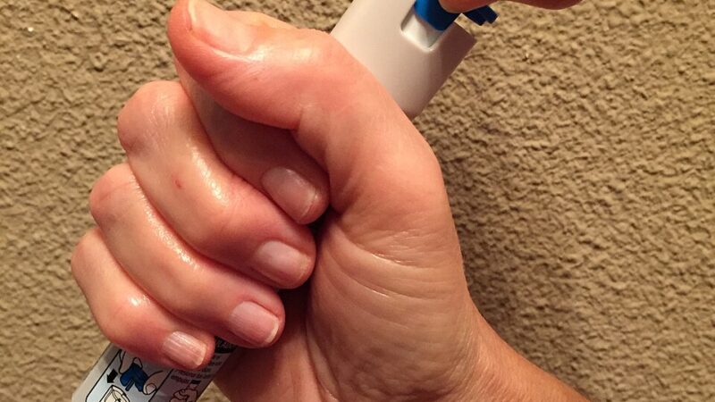 Hand holding an epinephrine autoinjector, the current standard of care for anaphylaxis