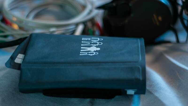A dark blue blood pressure cuff resting on a clinical surface with medical equipment nearby