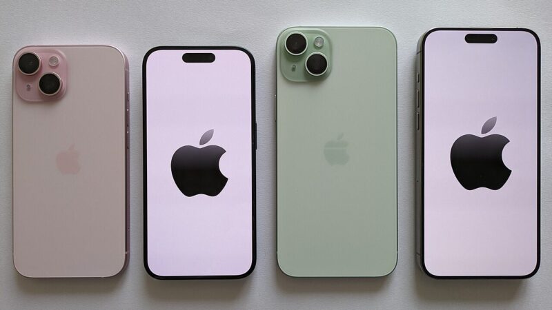 Four iPhone smartphones in pastel colours arranged in a row on a light surface