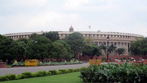 India's parliament building in New Delhi seen across gardens and a roadway
