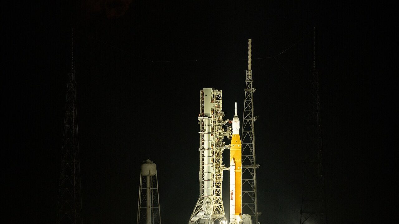 NASA SLS rocket on launch pad with moon rising above