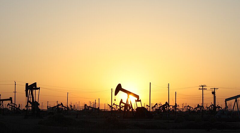 Oil pumpjacks silhouetted against the setting sun in an oil field