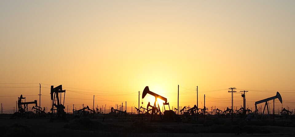 Oil pumpjacks silhouetted against the setting sun in an oil field